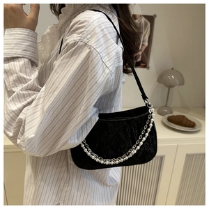 Detail of black textured baguette bag with metallic silver and pearl chain straps