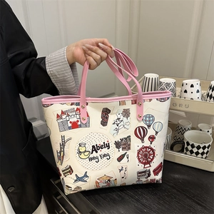Borsa tote con illustrazioni colorate di viaggi e manici rosa in ambiente interno