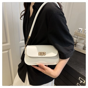 Close-up of white leather shoulder bag featuring gold woven buckle and metal chain strap