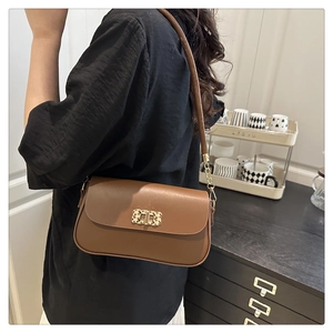 Detail of caramel brown leather handbag with gold textured twist lock and strap