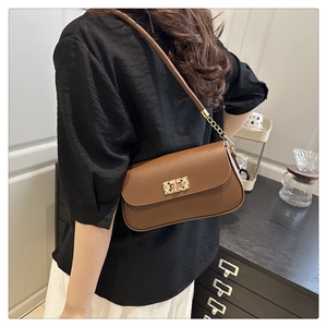 Detail of vintage brown leather bag featuring a gold metal buckle and chain strap