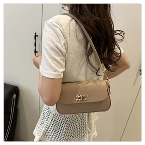Detail of elegant brown shoulder bag with golden woven buckle and chain strap on model
