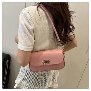Detail of pink faux leather crossbody bag featuring a golden geometric clasp and metal chain