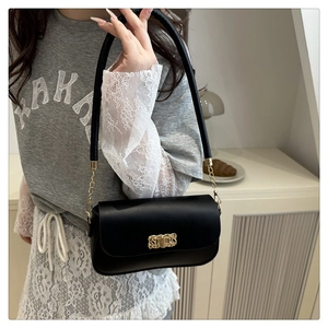Détail d'un sac sous le bras noir minimaliste avec une boucle en métal doré tressé