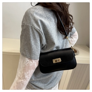 Detail view of stylish black leather crossbody bag with elegant gold woven metal lock
