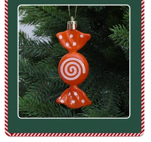 Detail von orangefarbenem Weihnachtsschmuck in Bonbonform mit weißen Wirbeln am Baum
