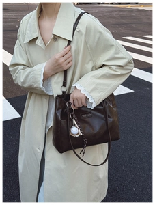 Detail of dark brown faux leather tote bag with baseball pendant and fashion tag