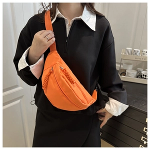 Detail van feloranje canvas crossbodytas met dubbele ritsen en geweven koordtrekkers