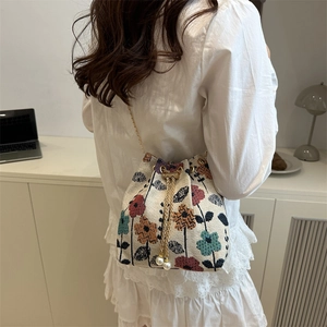 Ethnic retro floral drawstring bucket bag with pearl details and a gold chain strap