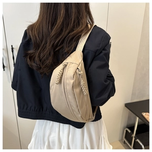 Detail van beige nylon halvemaantas met geweven ritstrekkers en brede schouderriem