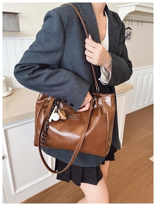 Detail view of a vintage brown leather tote bag with baseball charm and fashion label