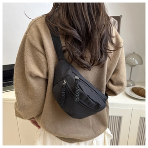 Close-up van zwarte canvas crossbodytas met gevlochten ritsen getoond in een lifestyle-omgeving