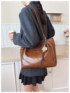 Close-up of a vintage dark brown tote bag with fashion tag and sporty charm detail