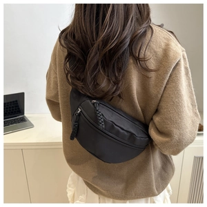Detailopname van zwarte crossbody heuptas met koordritsen gedragen door een model