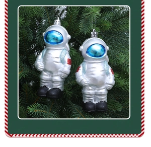 Close-up of silver astronaut Christmas ornaments hanging on a green festive tree