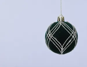 Dettaglio pallina di Natale floccata verde scuro con motivi geometrici argento e cappuccio oro