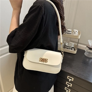 White minimalist crossbody bag with gold hardware buckle and chain strap on a model