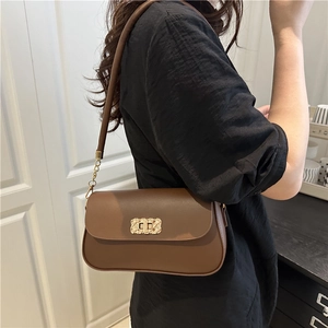 Caramel brown leather shoulder bag with gold woven buckle shown on model from a side angle