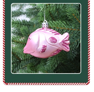 Détail d'un ornement de poisson rose perlé avec paillettes sur une branche de sapin