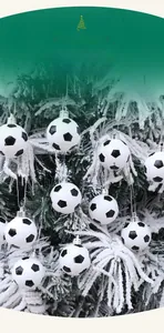 Close-up of black and white soccer ball ornaments hanging on a snowy Christmas tree