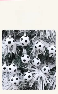Close-up of black and white soccer-shaped Christmas balls hanging on a snowy tree branch