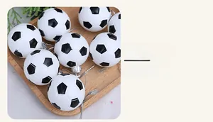 Detail of black and white soccer ball ornaments with silver hanging ropes on pine branches