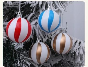 Detalle de bolas de Navidad a rayas rojas, azules y doradas en un árbol nevado