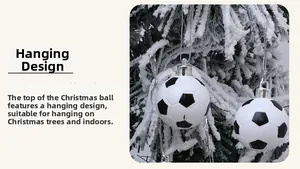 Detail of two black and white soccer ball Christmas ornaments hanging on a snowy pine tree