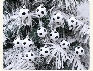 Close-up of soccer ball Christmas ornaments hanging on a snowy tree branch with silver strings