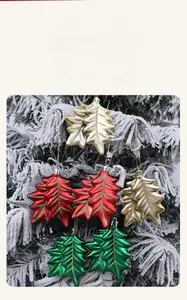 Detailed view of leaf-shaped glitter Christmas ornaments on a snowy pine tree branch