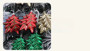 Close-up of glitter-edged holly leaf ornaments hanging on a snow-covered branch