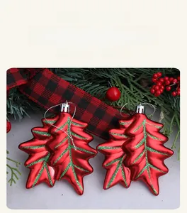 Detail of red leaf Christmas ornaments with green glitter accents and silver hanging loops