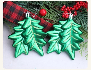 Detailed view of two green leaf-shaped Christmas ornaments with matte metallic finish