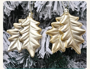 Detail of golden leaf Christmas ornaments with glitter veins on snowy pine branches