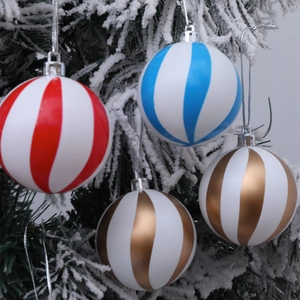 Bolas de Navidad con rayas rojas azules y doradas colgadas en un árbol nevado