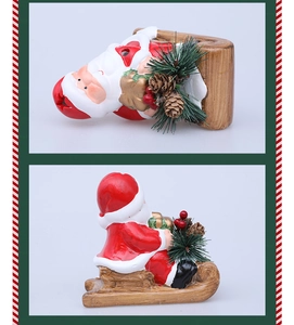 Close-up of ceramic Santa Claus on sled with pine cones and berries decoration