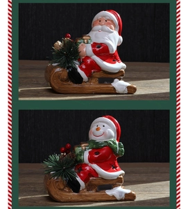 Detail of ceramic Santa Claus and snowman figurines on sleds with festive pine needles
