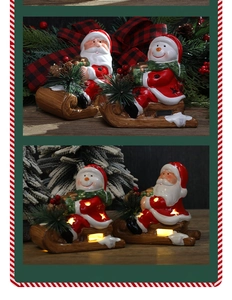 Close-up of LED glowing ceramic Santa and snowman on sleigh with star cutouts
