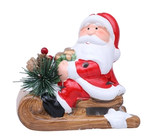 Close-up of a ceramic Santa Claus in a sled with pine cones and festive berries