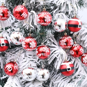 Red and silver hand-painted Christmas balls with HO HO prints hanging on a snowy tree branch