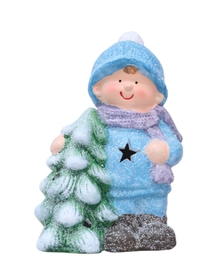 Close-up of a festive ceramic boy figurine holding a snowy Christmas tree with star cutout