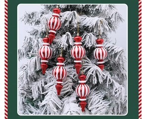 Set de seis adornos navideños con rayas rojas y blancas colgados en un árbol nevado