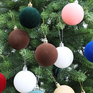 Flocked velvet Christmas ball ornaments in assorted colors hanging on a festive tree branch