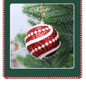 Close-up of a red glitter Christmas ball with white ribbon and pearls on a pine branch
