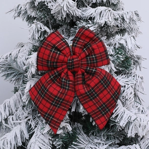 Classic red and black plaid Christmas bow ornament on a snowy green Christmas tree