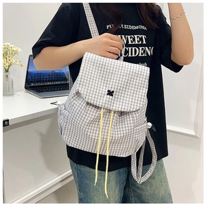 Close-up of a checkered canvas backpack featuring yellow drawstrings and geometric patch