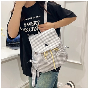 Detail of grey plaid backpack featuring vibrant yellow drawstring and side pocket