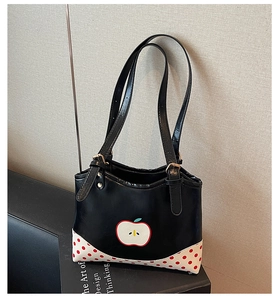 Detail of black tote bag featuring apple graphic and red polka dot patchwork corners