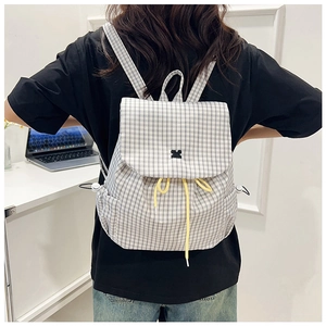 Detail of grid pattern backpack with drawstring closure worn by model in office