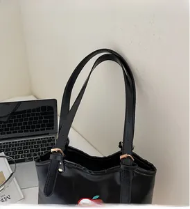 Detail of sturdy black tote bag handles with cute red apple pattern and gold hardware